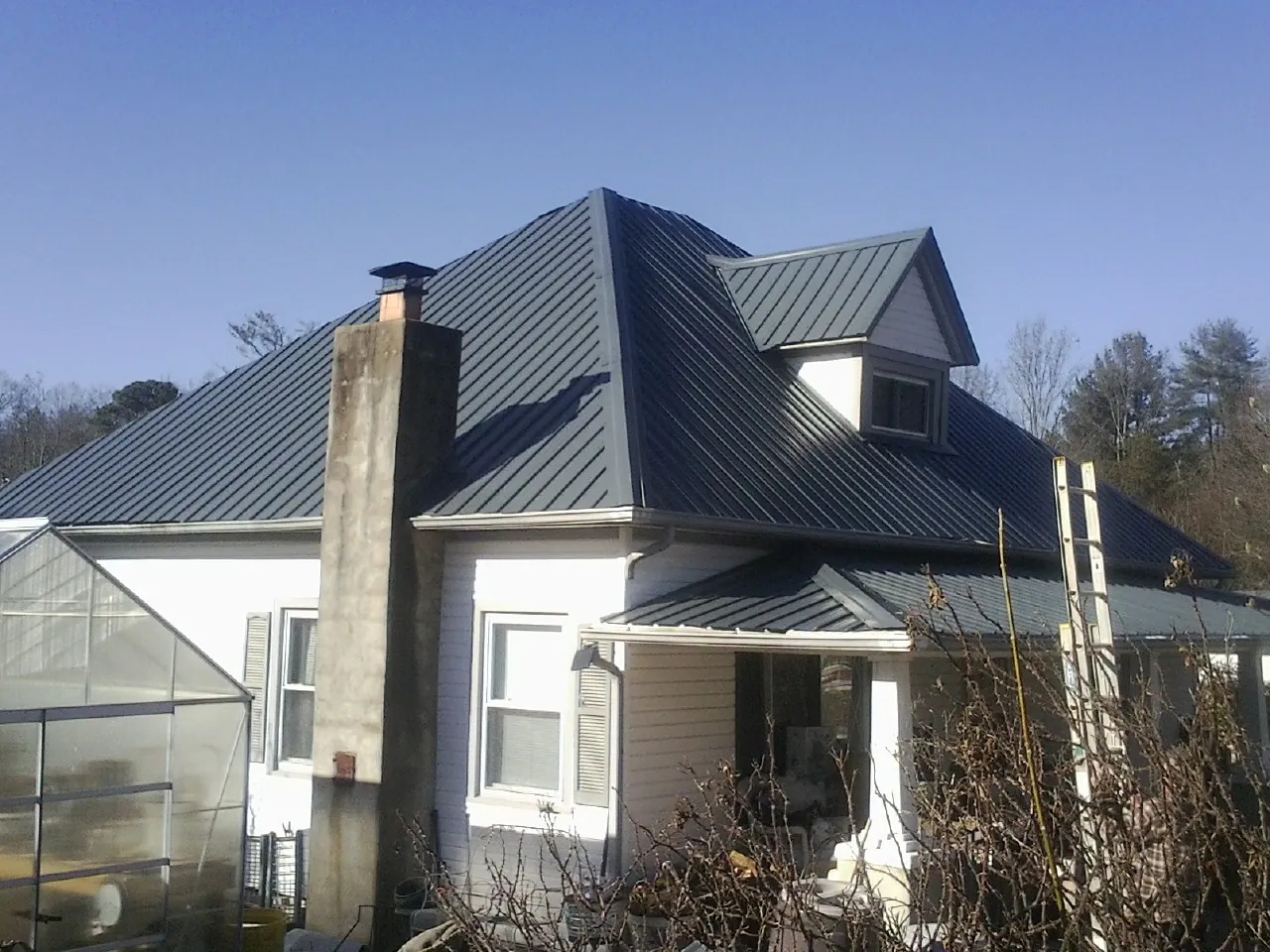 Dark blue standing seam metal roof on a white farmhouse with dormer — Slate & Tile Roof Repair by Roofing Brothers in Speer