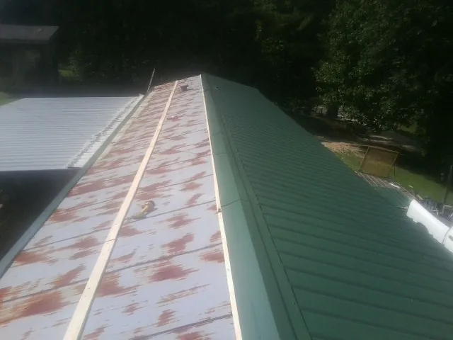 Old rusted panels beside newly installed green metal roofing — Wind Damage Roof Repair by Roofing Brothers in Speer