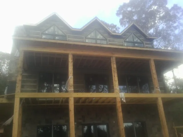 Dormers and porch framing on a large log home under construction — Roof Coating work by our crew in Speer