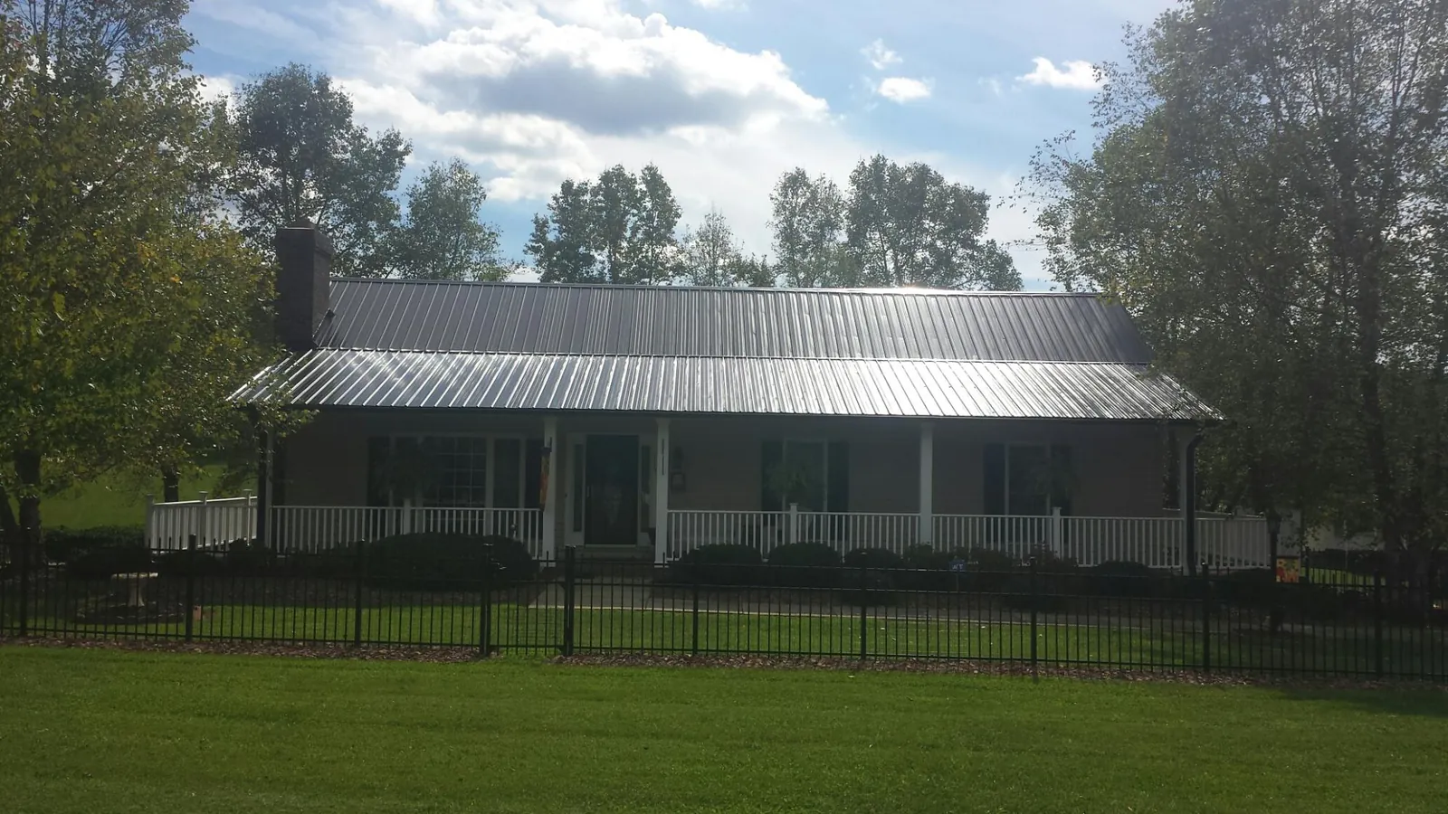 Gray metal roof on a brick ranch with a full width front porch — Gutter Guard Installation work by our crew in Speer