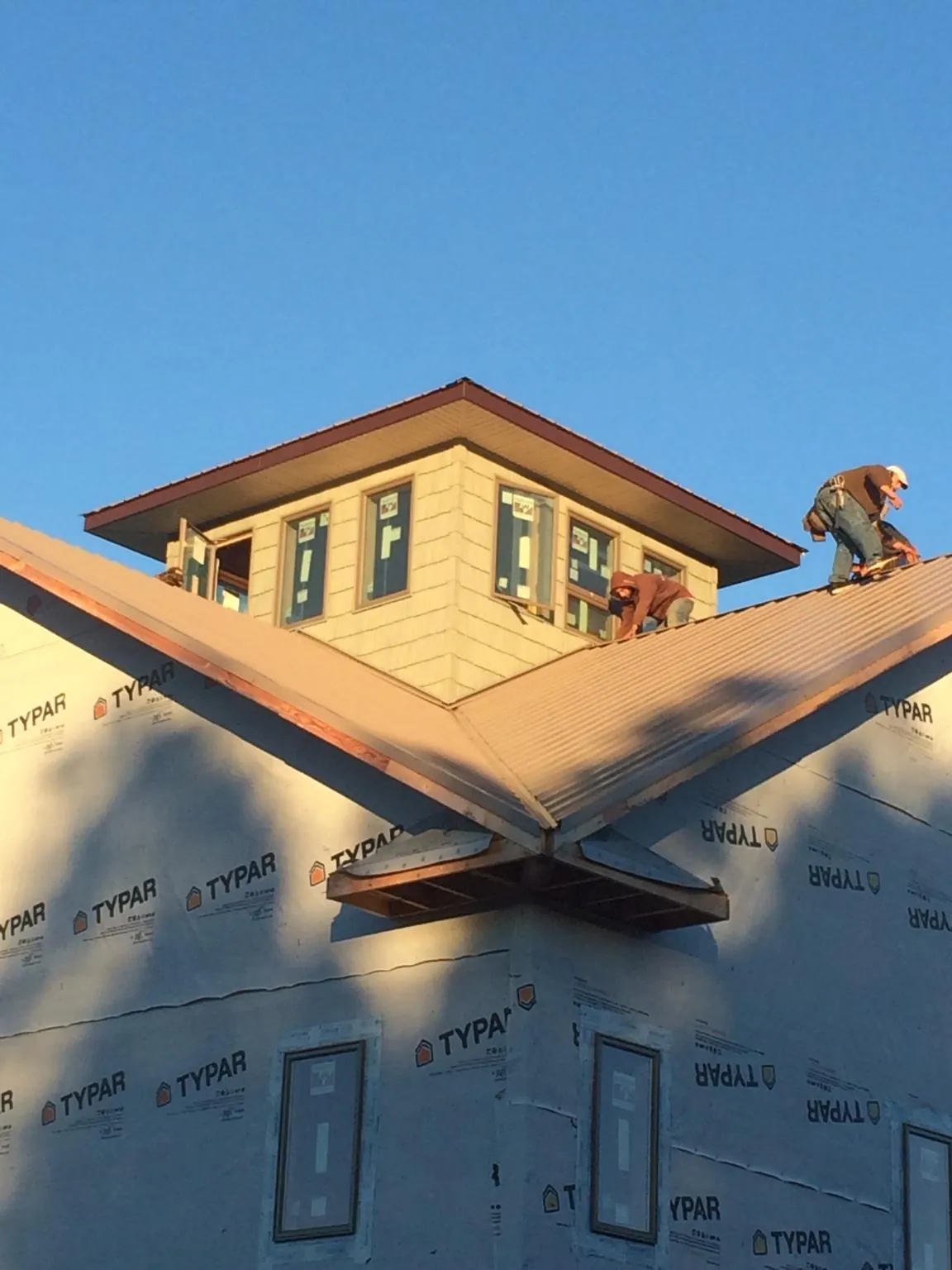 Roofers working around a rooftop cupola on a new metal roof at sunset — Roof Waterproofing in Speer by Roofing Brothers